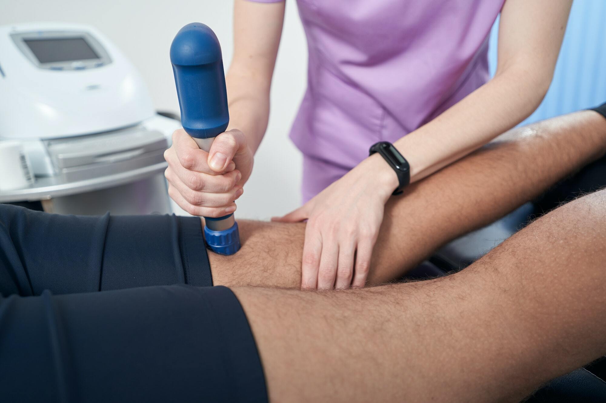 Doctor performing shockwave therapy procedure in clinic