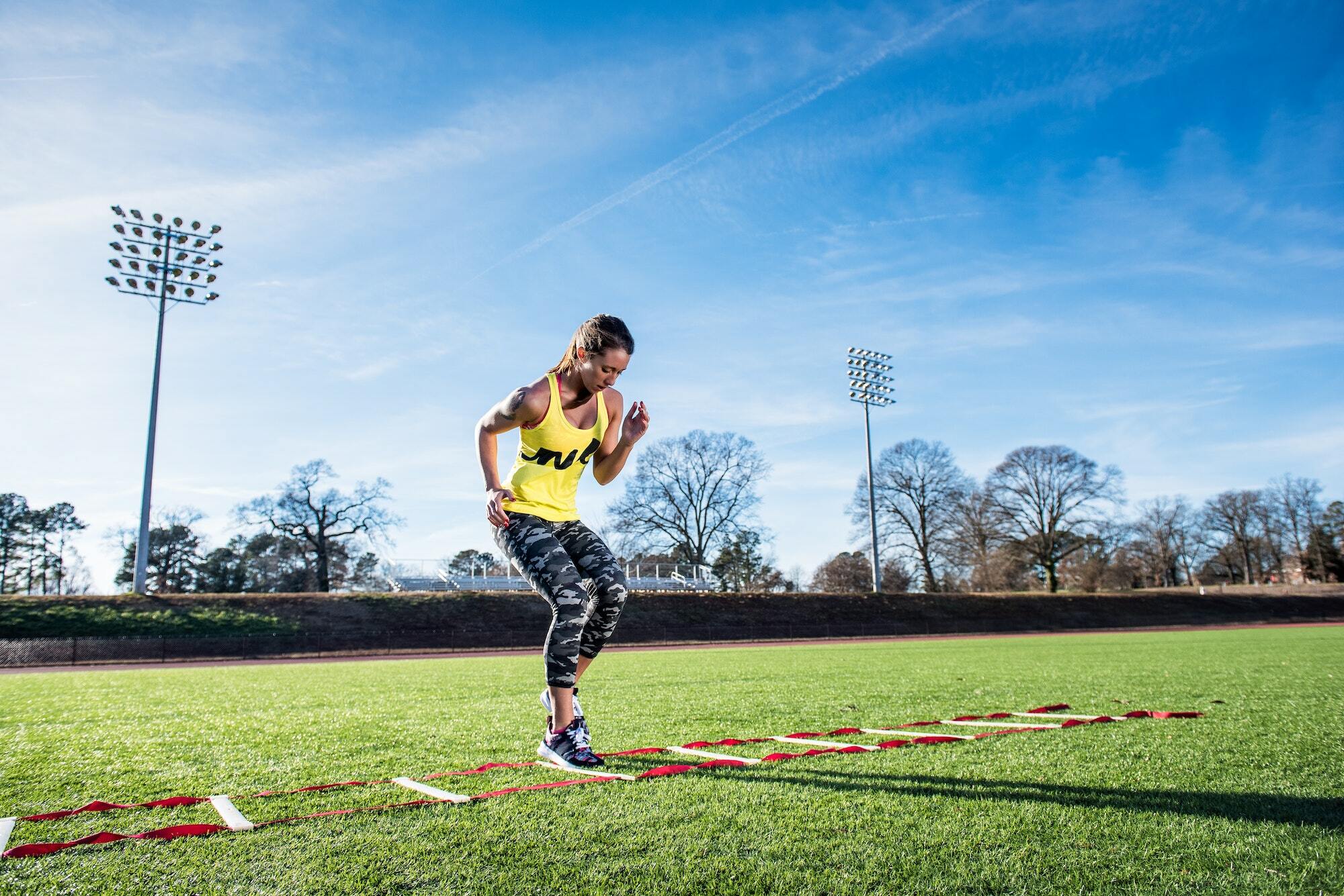 Young female athlete training with agility ladder on sports field